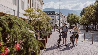 Un uomo e una donna spingono le loro biciclette per Brunico