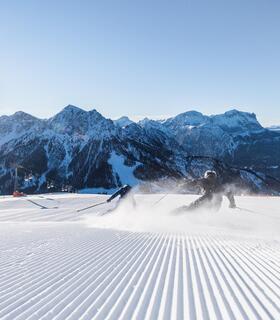 Two skiers are skiing down a slope on Kronplatz