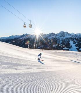Two skiers are skiing down a slope on Kronplat