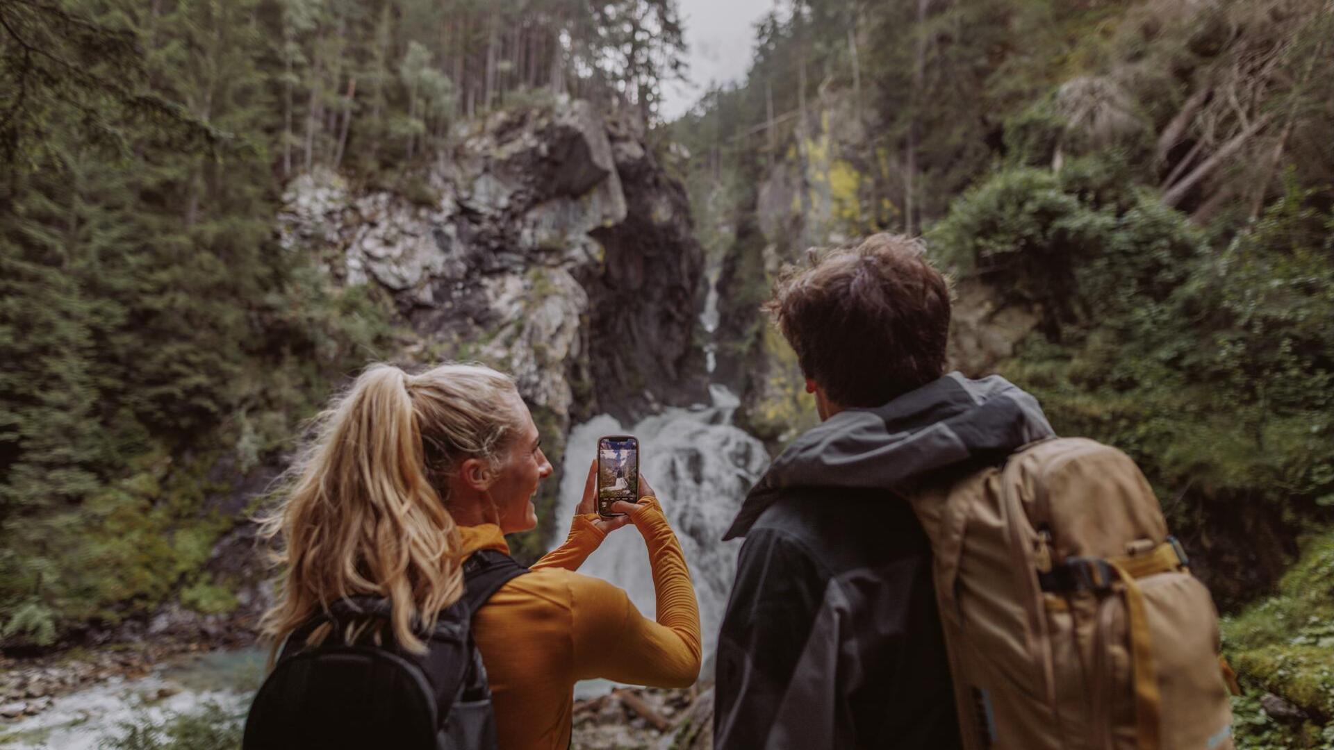 Ein Mann und eine Frau fotografieren einen Wasserfall